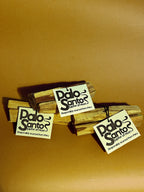 Three Palo Santo sticks with 'Palo Santo' labels on a brown background