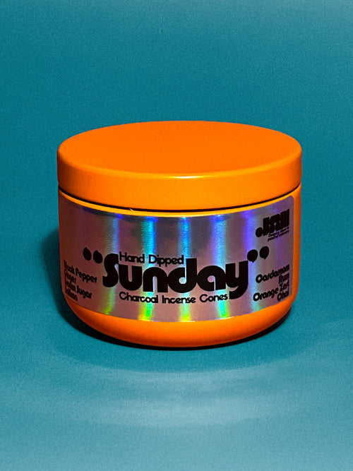 Orange container with 'Sunday' scent hand dipped charcoal incense cones branding on a blue background
