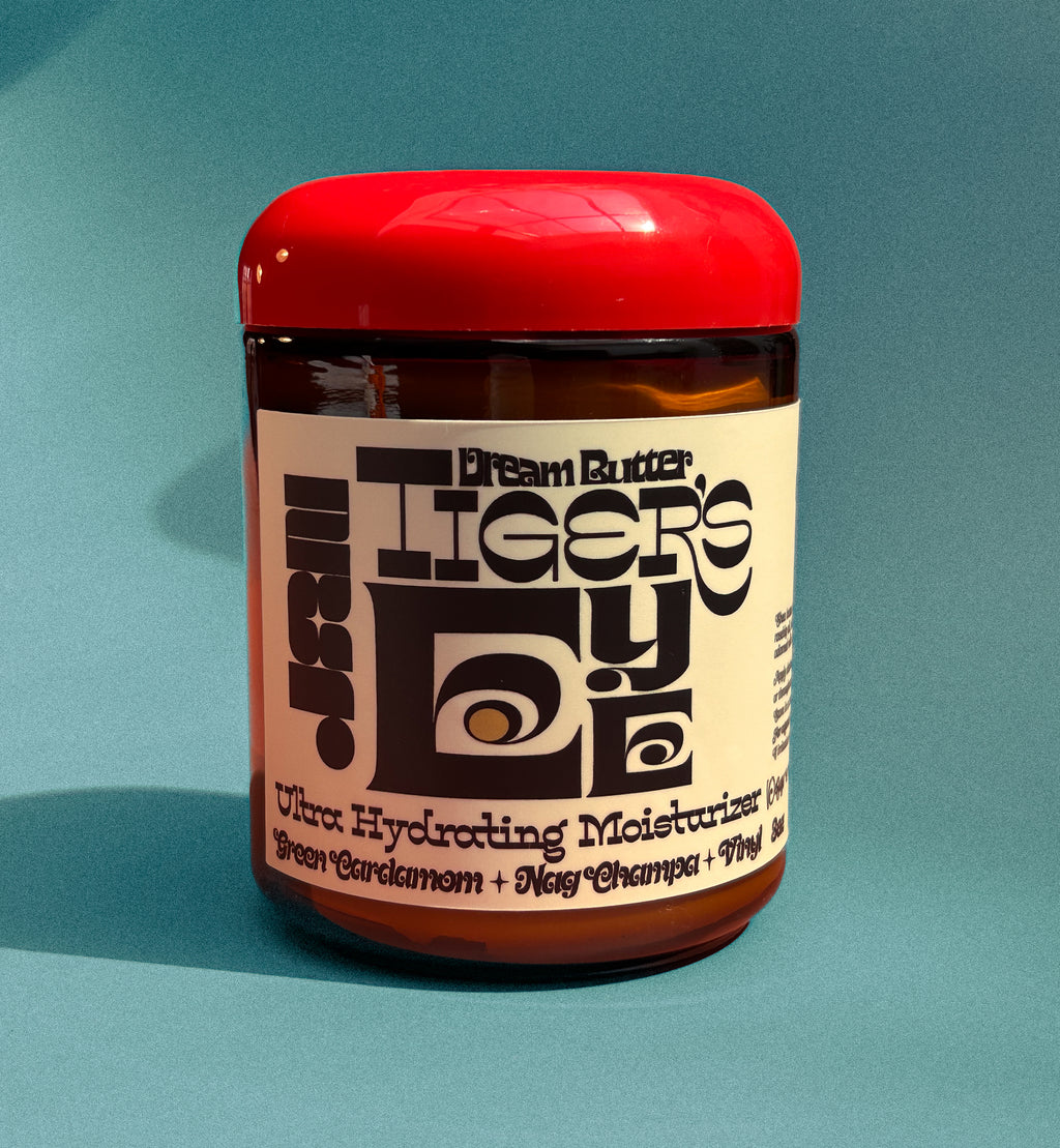 Jar of Dream Butter Tiger's Eye Ultra Hydrating Moisturizer on a teal background