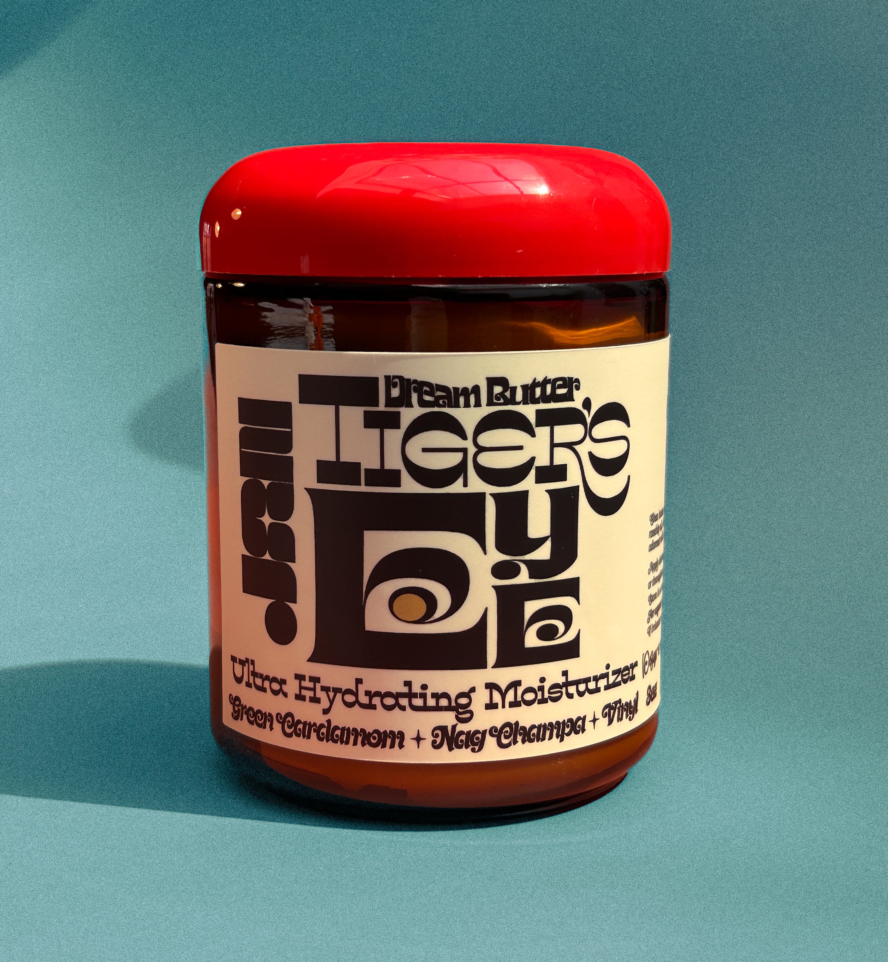 Jar of Dream Butter Tiger's Eye Ultra Hydrating Moisturizer on a teal background