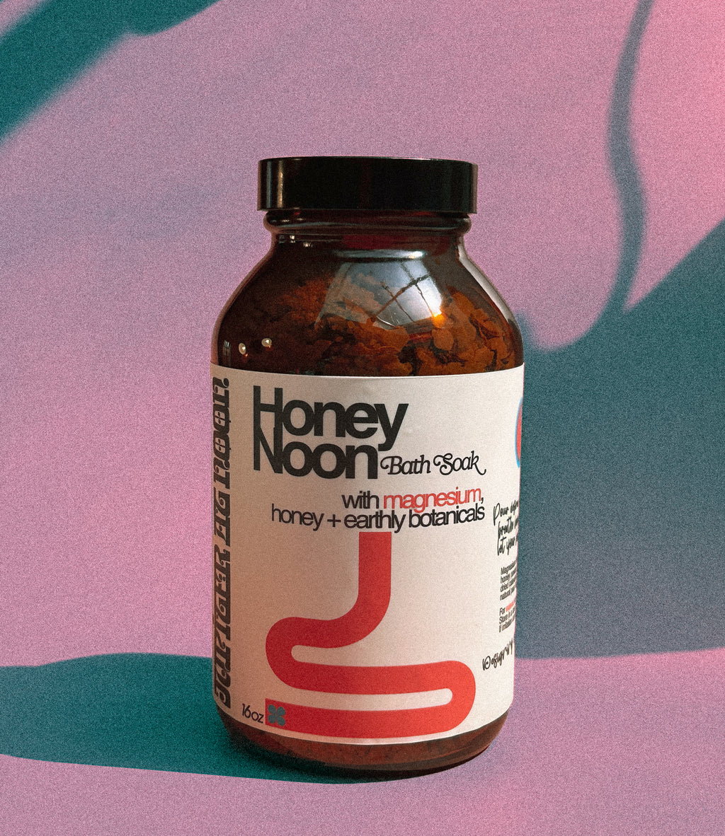Bottle of Honey Noon Bath Soak with a colorful abstract background