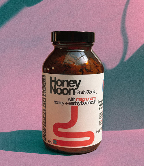 Bottle of Honey Noon Bath Soak with a colorful abstract background