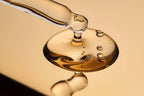 Close-up of a dropper with liquid on a reflective surface