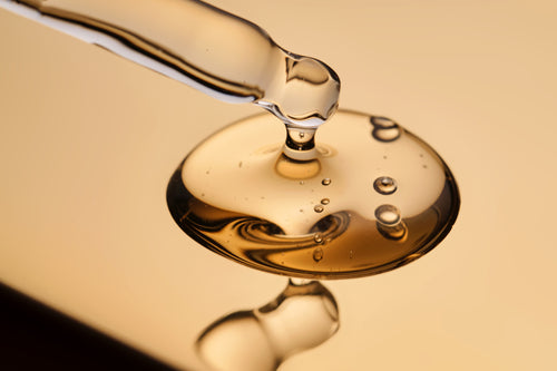 Close-up of a dropper with liquid on a reflective surface